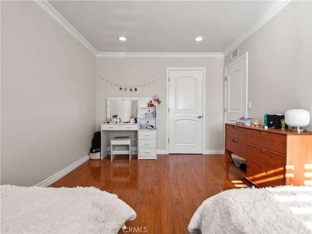 bedroom featuring visible vents, crown molding, baseboards, and wood finished floors