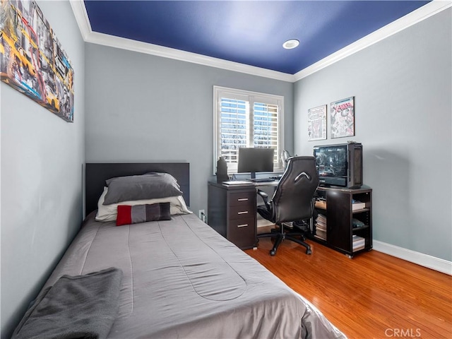 bedroom featuring ornamental molding, baseboards, and wood finished floors