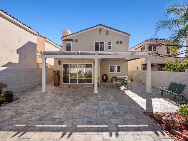 rear view of property featuring stucco siding, a pergola, a fenced backyard, a chimney, and a patio area