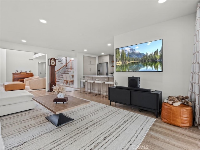 living area with recessed lighting, light wood-type flooring, and stairs