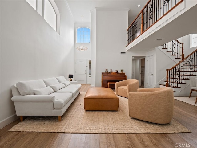 living area with stairs, visible vents, wood finished floors, and baseboards