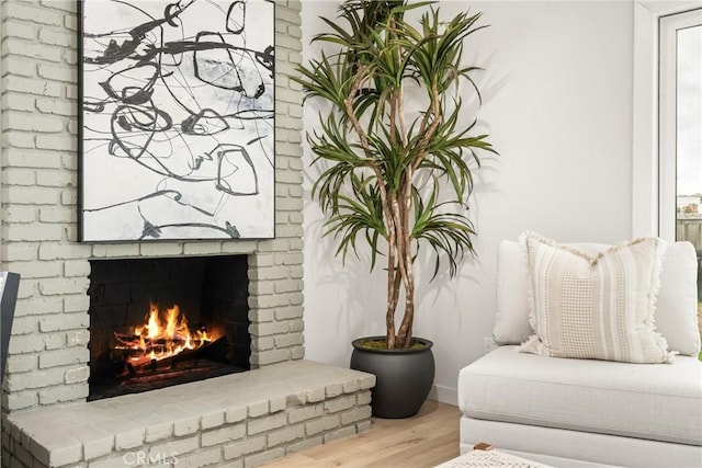 living area with a brick fireplace and wood finished floors