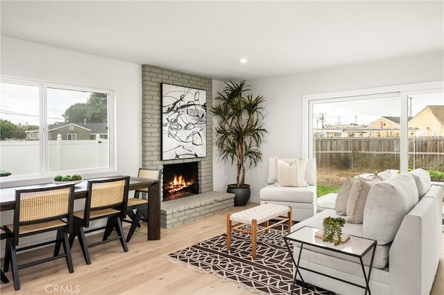 living area featuring recessed lighting, a brick fireplace, and wood finished floors