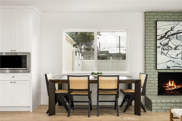 dining room with light wood finished floors and a fireplace