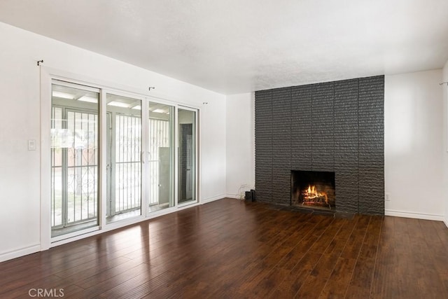 unfurnished living room featuring baseboards, wood finished floors, and a fireplace