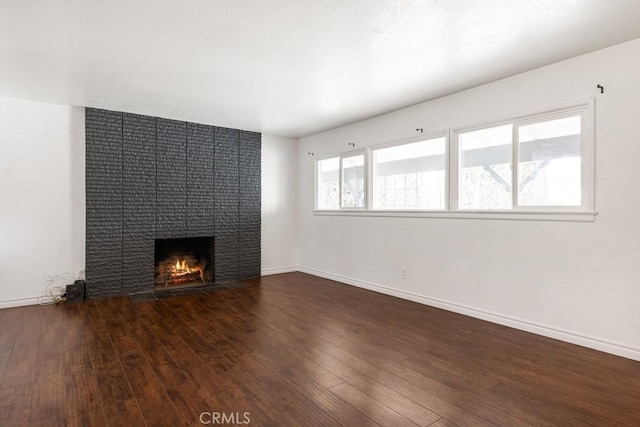 unfurnished living room with a fireplace, baseboards, and wood-type flooring