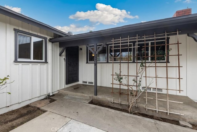 doorway to property with board and batten siding and a chimney