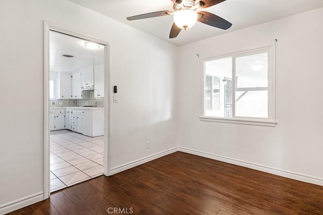 empty room with baseboards, a ceiling fan, and wood finished floors