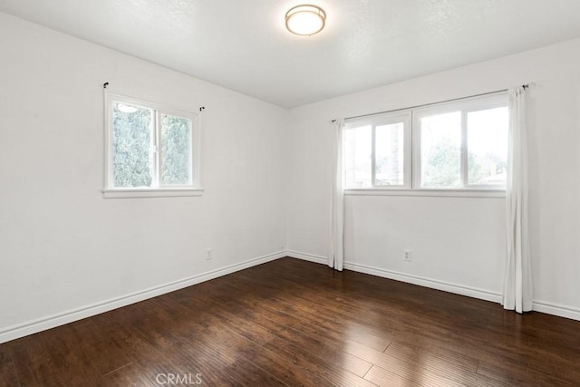 spare room featuring baseboards and wood finished floors