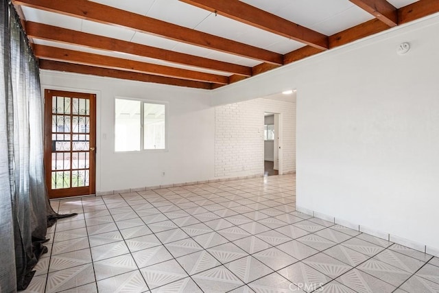 spare room with light tile patterned floors, beam ceiling, brick wall, and baseboards