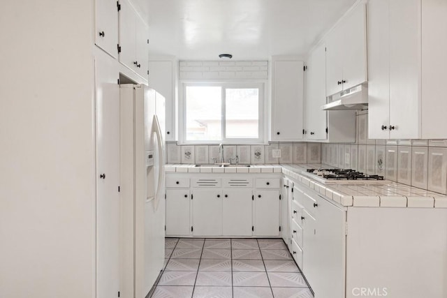 kitchen with under cabinet range hood, white appliances, tasteful backsplash, and a sink