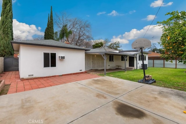 back of house featuring crawl space, fence, a lawn, and a gate