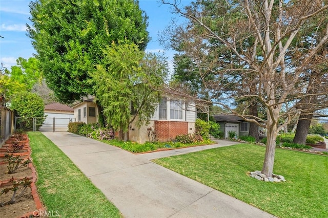 obstructed view of property with a front yard, a gate, fence, a detached garage, and brick siding