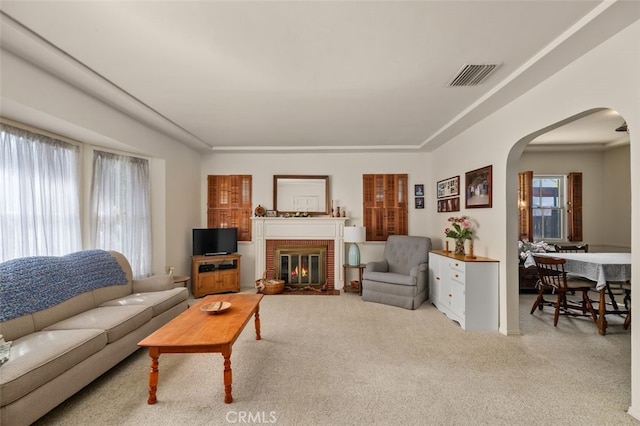 carpeted living area featuring visible vents, arched walkways, and a fireplace