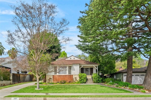 view of front of house featuring brick siding, a front lawn, and fence