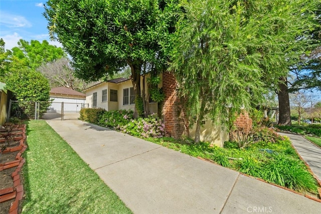 view of side of property featuring a gate, fence, a yard, and stucco siding