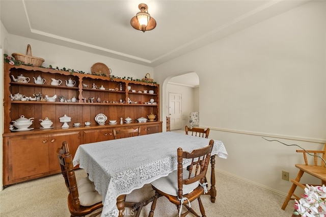 dining space with light colored carpet, baseboards, and arched walkways