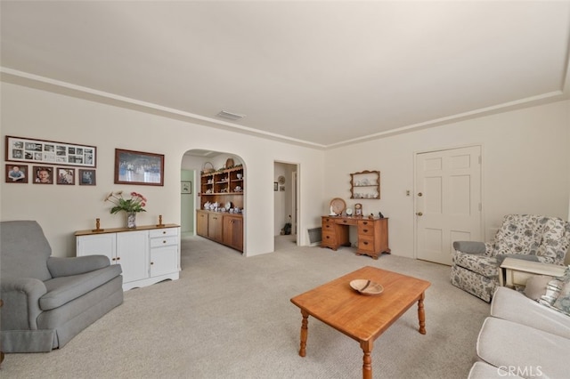 living room with built in features, arched walkways, visible vents, and light carpet