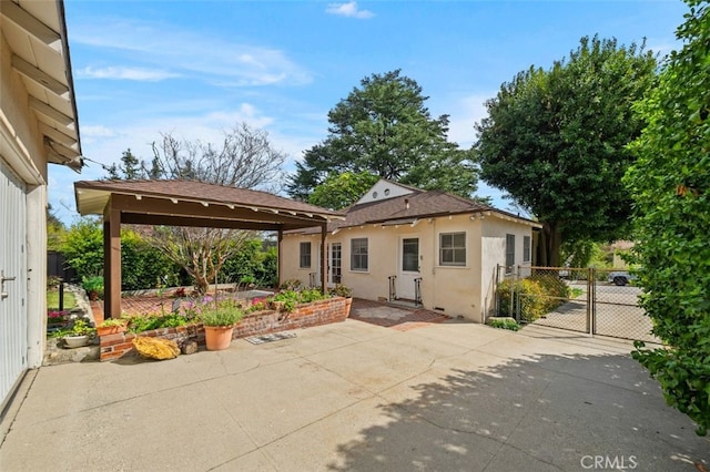 exterior space with a gate, stucco siding, fence, and a patio area