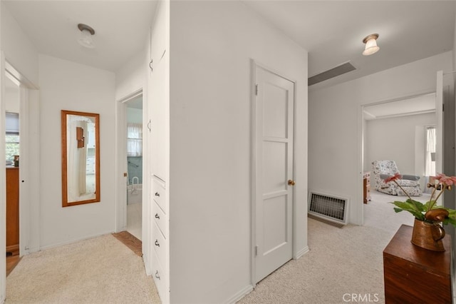 hallway featuring heating unit and light colored carpet