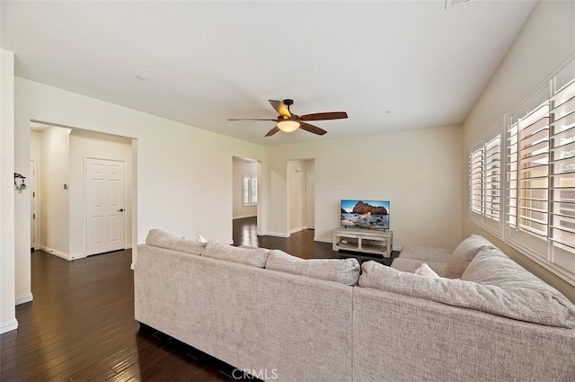 living room featuring a wealth of natural light, baseboards, dark wood finished floors, and a ceiling fan