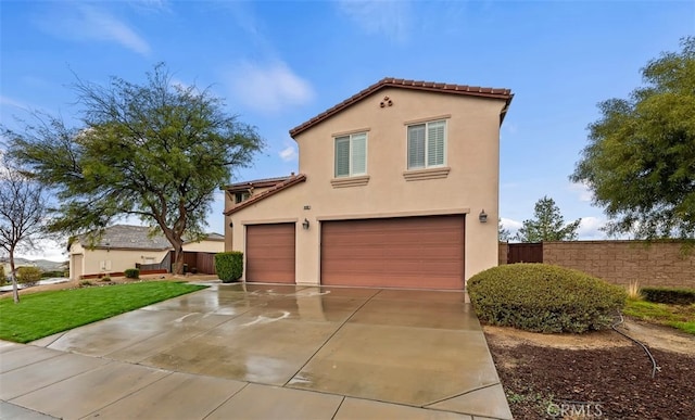 mediterranean / spanish house featuring fence, a tile roof, concrete driveway, stucco siding, and an attached garage