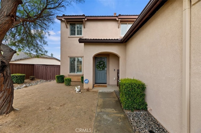 property entrance featuring stucco siding and fence