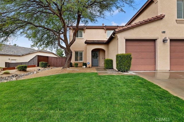 mediterranean / spanish-style home featuring fence, a tiled roof, concrete driveway, a front yard, and stucco siding