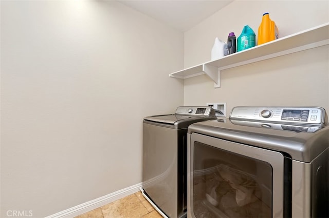 washroom featuring baseboards, light tile patterned flooring, laundry area, and washing machine and clothes dryer