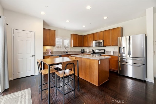 kitchen featuring brown cabinetry, a kitchen island, stainless steel appliances, and dark wood-style flooring