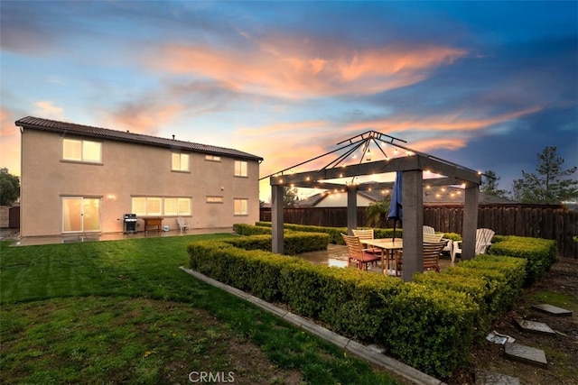 back of property at dusk featuring a gazebo, a yard, fence, and stucco siding