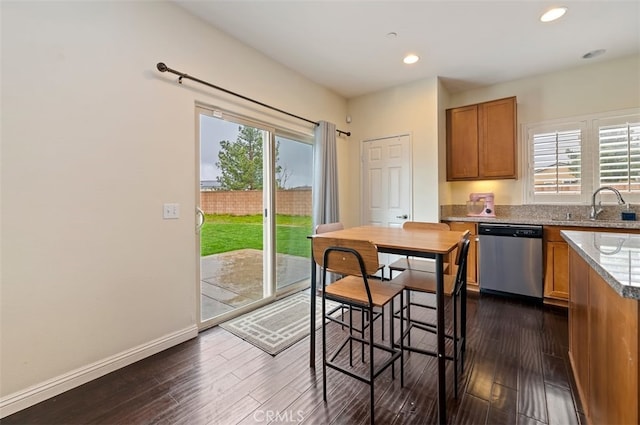 kitchen with a sink, brown cabinets, dishwasher, and dark wood-style flooring