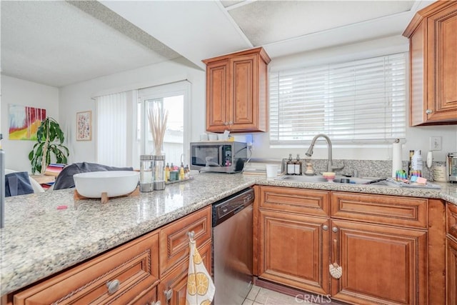 kitchen featuring a sink, stainless steel appliances, brown cabinets, and light stone counters