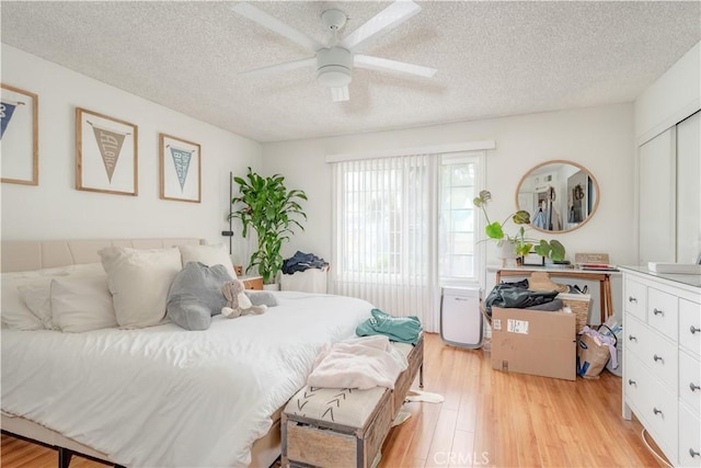 bedroom with light wood finished floors, a closet, a textured ceiling, and ceiling fan