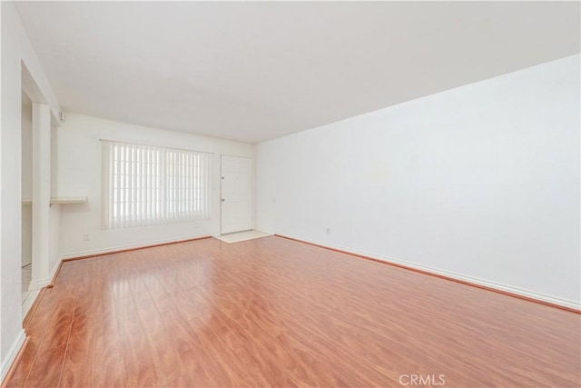 empty room featuring baseboards and light wood finished floors