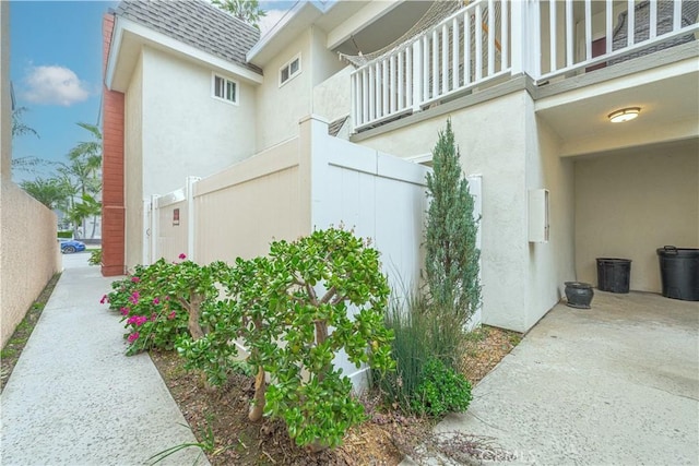 view of side of property with fence, roof with shingles, and stucco siding