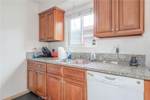 kitchen with brown cabinetry, dishwasher, light countertops, and a sink