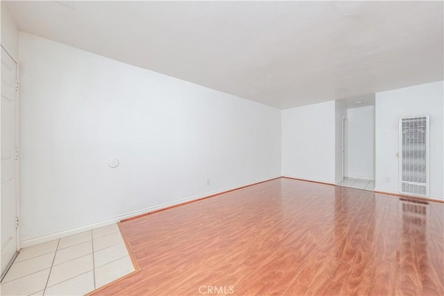 spare room with baseboards and light wood finished floors