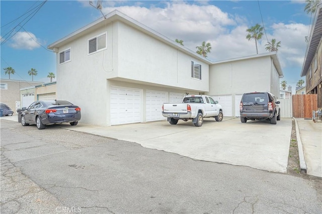 view of property exterior featuring a garage, fence, driveway, and stucco siding