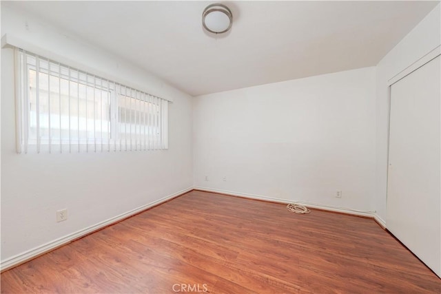 spare room featuring baseboards and wood finished floors