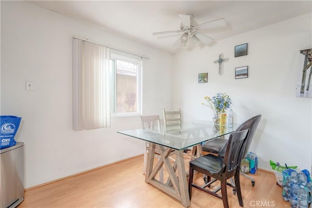 dining room with baseboards, light wood-type flooring, and a ceiling fan