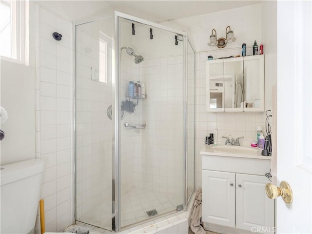 bathroom with decorative backsplash, a shower stall, toilet, and vanity