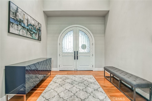 entryway with french doors, baseboards, arched walkways, and wood finished floors