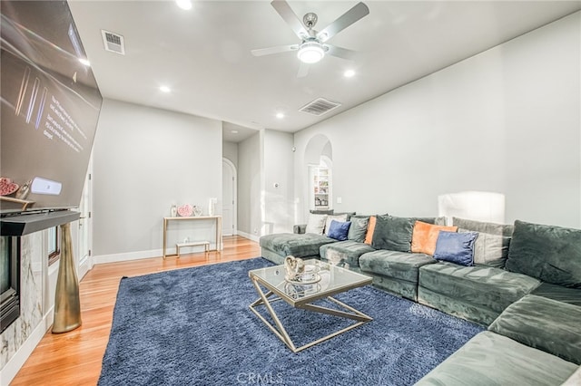 living room with a ceiling fan, wood finished floors, visible vents, and arched walkways