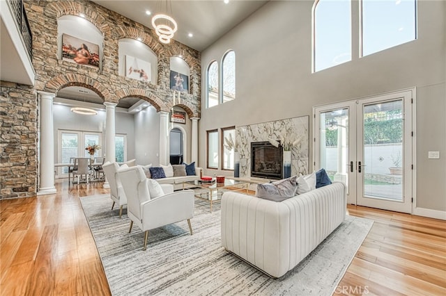 living room with decorative columns, a fireplace, light wood-type flooring, and a wealth of natural light