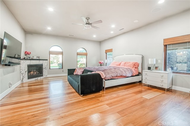 bedroom with recessed lighting, light wood-type flooring, baseboards, and a fireplace