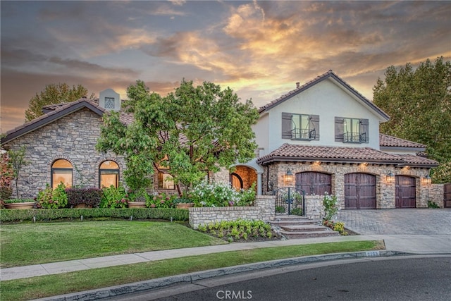 view of front facade featuring a lawn, stucco siding, decorative driveway, stone siding, and an attached garage