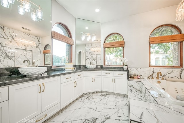 bathroom featuring marble finish floor, a sink, recessed lighting, a tub with jets, and double vanity