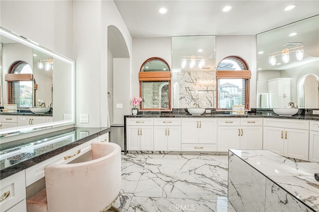 bathroom featuring recessed lighting, plenty of natural light, marble finish floor, and a freestanding bath