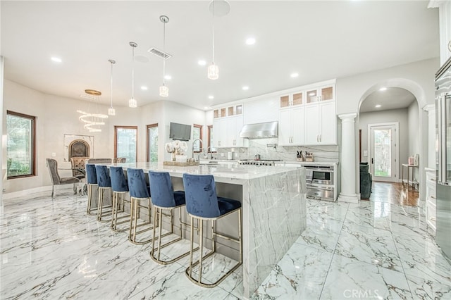 kitchen with visible vents, marble finish floor, ventilation hood, decorative backsplash, and ornate columns